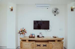 um quarto com uma mesa e uma televisão na parede em Hoan Hao Hotel em Ha Giang