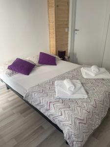 ein Bett mit zwei Handtüchern und lila Kissen darauf in der Unterkunft Camera Enaj in Cadenazzo