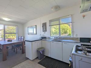 a kitchen with white cabinets and a table and a sink at Springfield Bliss in Rotorua