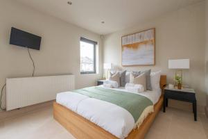 a bedroom with a large bed and a flat screen tv at Elegant 1-BR Retreat in Ilford Centre in Ilford
