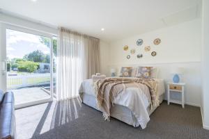 a bedroom with a bed and a sliding glass door at The Mayflower Cottage in Te Anau