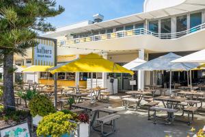 an outdoor patio with tables and umbrellas in front of a building at Apartment 201 - Fremantle studio apartment with ocean and harbour views in Fremantle