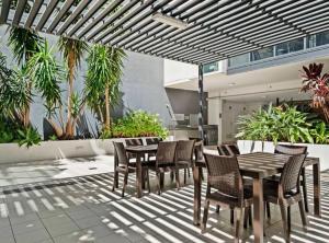 a patio with a wooden table and chairs and plants at Luxury City Center King Bed Apartment and Study in Brisbane