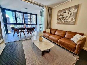 a living room with a brown couch and a table at Luxury City Center King Bed Apartment and Study in Brisbane