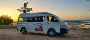 een wit busje geparkeerd op een strand met een palmboom bij The Dugongs' Rest in Horn