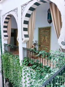 uma casa com uma varanda com plantas e uma porta em El Patio Courtyard House em Tunes