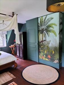 een slaapkamer met een muurschildering van een palmboom bij Chambres d'Hôtes Le Grismoustier in Veulettes-sur-Mer