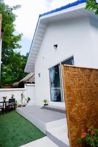 une maison blanche avec une porte en bois et une cour dans l'établissement Kingsacre, à Nai Yang Beach