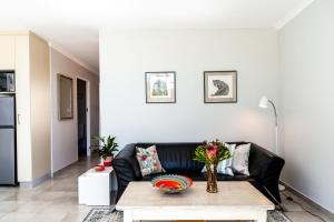 a living room with a black couch and a table at Tortelduif Cottage in Stellenbosch