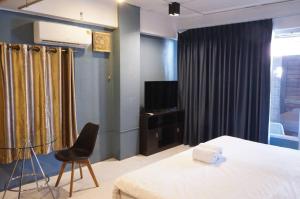 sypialnia z łóżkiem, telewizorem i krzesłem w obiekcie isleep guesthouse w mieście Chiang Mai