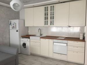 cocina con armarios blancos, lavadora y secadora en A cozy and modern apartment Krasno selo, en Sofía