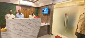 three men standing behind a counter in a bathroom at Hotel SolStay Inn Residency in Thane