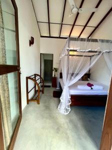 - une chambre avec un lit et une moustiquaire dans l'établissement Sham Surf House -Madiha, à Matara