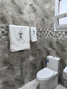 a bathroom with a toilet and towels on the wall at Bareeq Rest House in Barka