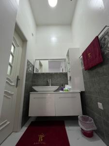 a bathroom with a white sink and a red rug at Bareeq Rest House in Barka