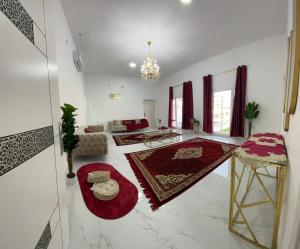 a living room with white walls and red carpets at Bareeq Rest House in Barka