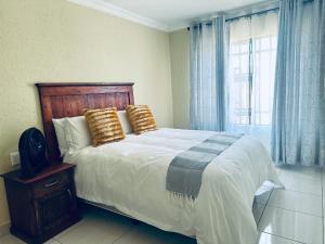 ein Schlafzimmer mit einem großen Bett mit Kissen und einem Fenster in der Unterkunft MBT Guesthouses in Ga-Mothiba