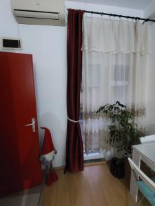um quarto com uma janela com uma cortina vermelha e uma planta em Cozy Max Studio em Jagodina
