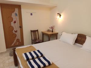 a bedroom with a large white bed and a chair at SAI HOMESTAY in Agonda