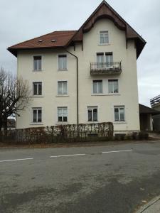 a large white building with a wooden roof at Croix 1 in Le Noirmont