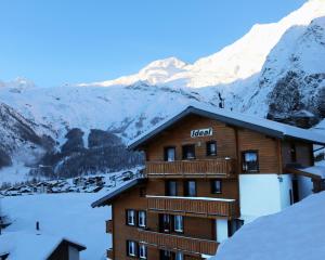 a hotel with snow covered mountains in the background at Chalet Ideal Saas-Fee in Saas-Fee