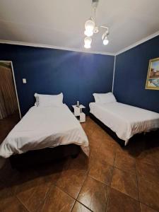 two beds in a room with a blue wall at Gae la boroko @legodi's in Brakpan