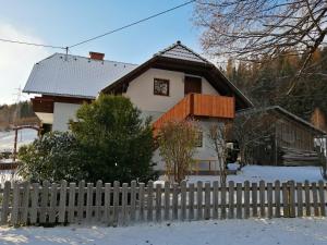 a white house with a fence in the snow at Apartment Moser in Lutzmannsdorf