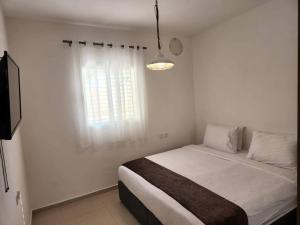 a white bedroom with a bed and a window at arie apartment in Eilat