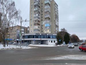 un grand bâtiment avec un parking en face de celui-ci dans l'établissement FULL HOUSE apart hotel, à Rivne