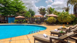 een zwembad met stoelen en parasols bij een hotel bij Oak Plaza Hotels East Airport in Accra