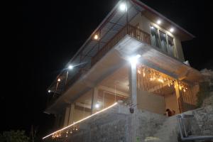 a house with lights on the side of it at night at Pyare Cafe Cottages And Tents in Gushaini