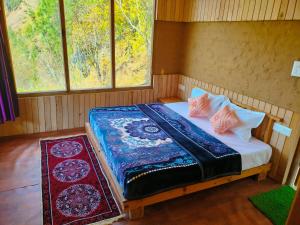 a bed in a room with two pillows and two windows at Pyare Cafe Cottages And Tents in Gushaini