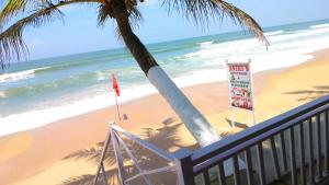 vistas a la playa con un cartel y una palmera en Anthy’s Guesthouse and Restaurant en Benaulim