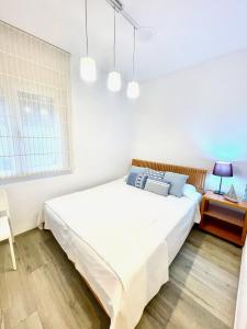 a bedroom with a large white bed and a desk at SeaHomes Vacations - NAUTIC MARITIME Apt in Blanes