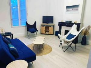 ein Wohnzimmer mit einem blauen Sofa und Stühlen und einem Kamin in der Unterkunft L'Ecrin de Lena in Épernay