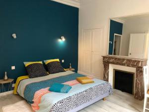 ein Schlafzimmer mit einem großen Bett und einem Kamin in der Unterkunft L'Ecrin de Lena in Épernay