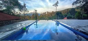 a swimming pool with blue water and mountains in the background at Green Garden Wayanad Villas in Vayittiri