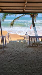 - une plage avec un palmier et l'océan dans l'établissement Anthy’s Guesthouse and Restaurant, à Benaulim