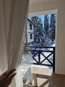 een persoon die uit een raam naar een huis kijkt bij Апартамент Лейк Вю, вила Флора, комплекс Маунтин лейк in Smolyan
