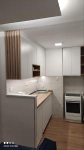 uma cozinha com armários brancos, um lavatório e um fogão em Apartman Noel Sarajevo em Sarajevo