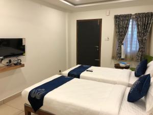 two beds in a hotel room with a tv at Hotel Amulya Regency in Bangalore