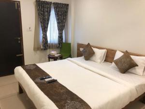 a bedroom with a large white bed and a window at Hotel Amulya Regency in Bangalore