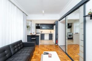 a living room with a black couch and a kitchen at G&B MANSION in Istanbul