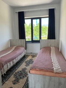 two beds sitting in a room with a window at Guest house Simiram in Cholpon-Ata