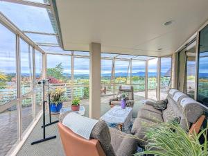 a living room with a couch and chairs and windows at Perfect for lake view and city view in Rotorua in Rotorua
