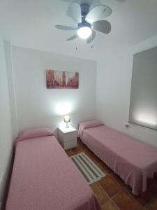 2 camas en una habitación con ventilador de techo en Atiko Welcome, en Arcos de la Frontera