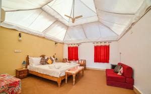斋沙默尔Lakhmana Desert Camp With Swimming Pool的卧室里有一张床，天花板上挂着红色的窗帘