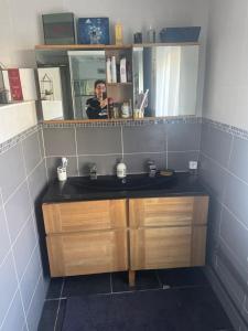 une femme prenant une photo d'un lavabo dans la salle de bains dans l'établissement chambre simple proche aéroport, à Pusignan
