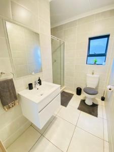 Baño blanco con lavabo y aseo en Deluxe one bedroom at the Blyde crystal lagoon, en Pretoria