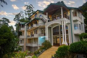 a large white house with stairs in front of it at Panorama Green View Hotel Nuwara Eliya in Nuwara Eliya